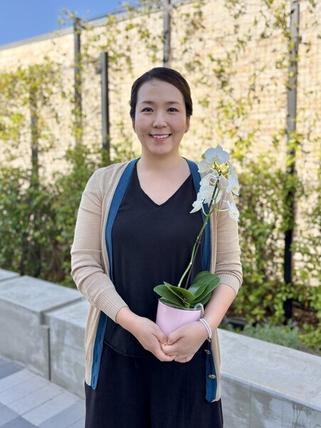 Regina Lee, 2026 Classified Employee of the Year, holding an orchid plant.
